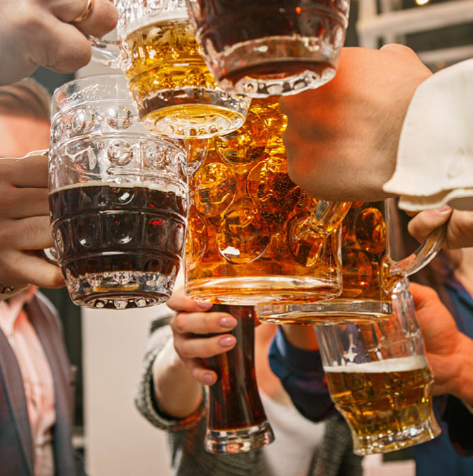 Group of friends enjoying evening drinks with beer on wooden table